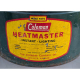 A vintage Coleman Heatmaster instant lighting lantern, model 457G, featuring a large yellow label with red lettering on a dark green metal body.