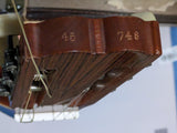 Close-up of a dark brown wooden guitar headstock with visible tuning pegs, strings, and engraved numbers 45 and 748 on the front.