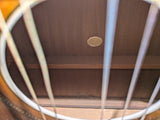 Close-up view of a guitar's soundboard and strings, showing the wood grain and a small round gold-toned emblem near the center.